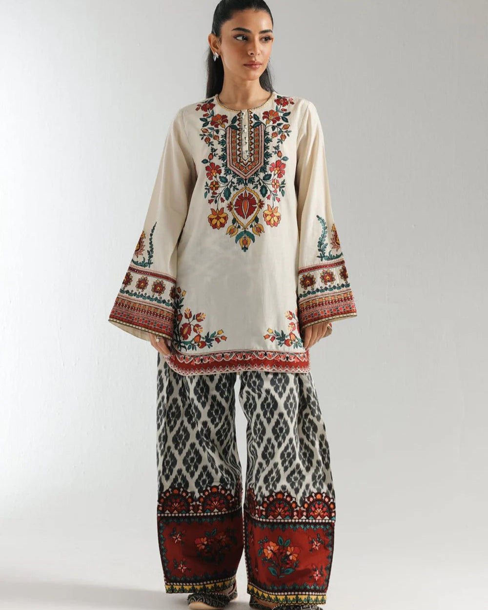 Woman wearing a traditional embroidered outfit with a plain background